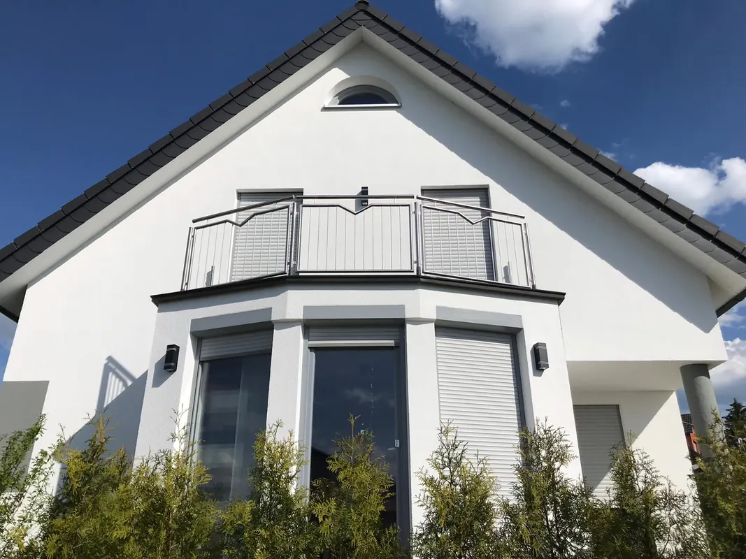 Einfamilienhaus mit weißer Fassade, Erker und Balkon