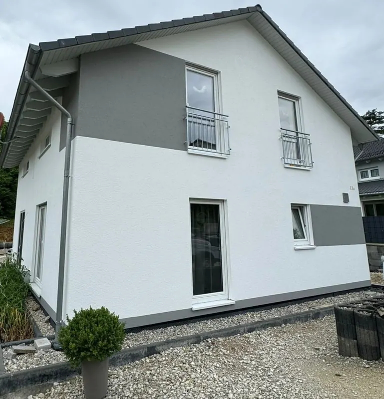 Wohnhaus mit weiß verputzter Fassade und grauen Akzentflächen