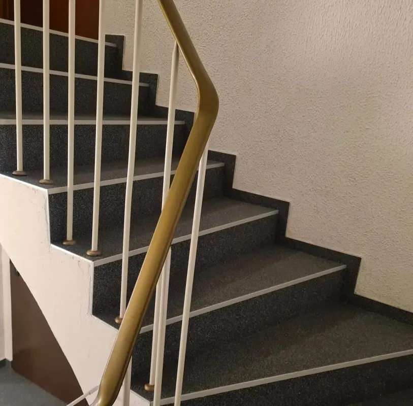 Treppenhaus mit dunkel belegten Stufen und weißem Geländer