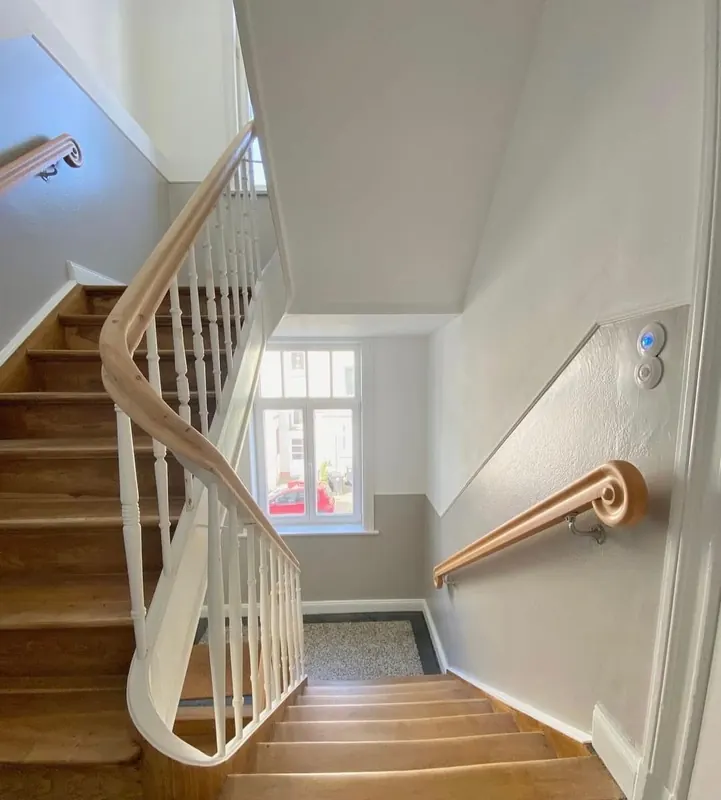 Treppenhaus mit Holztreppe, weißem Geländer und Handlauf