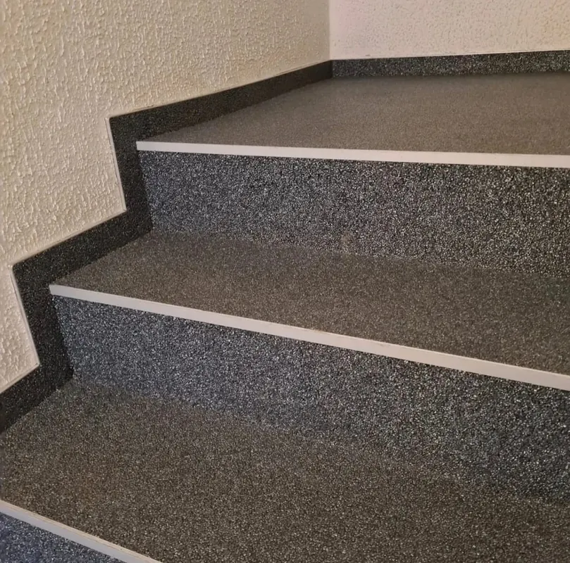 Treppenstufen mit dunklem, körnigem Belag und heller Kante