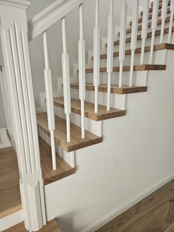 Treppe mit weißen Geländerstäben und Holzstufen